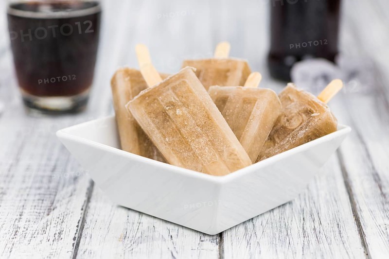 Fresh made Cola Popsicles on wooden background (selective focus, close-up shot)