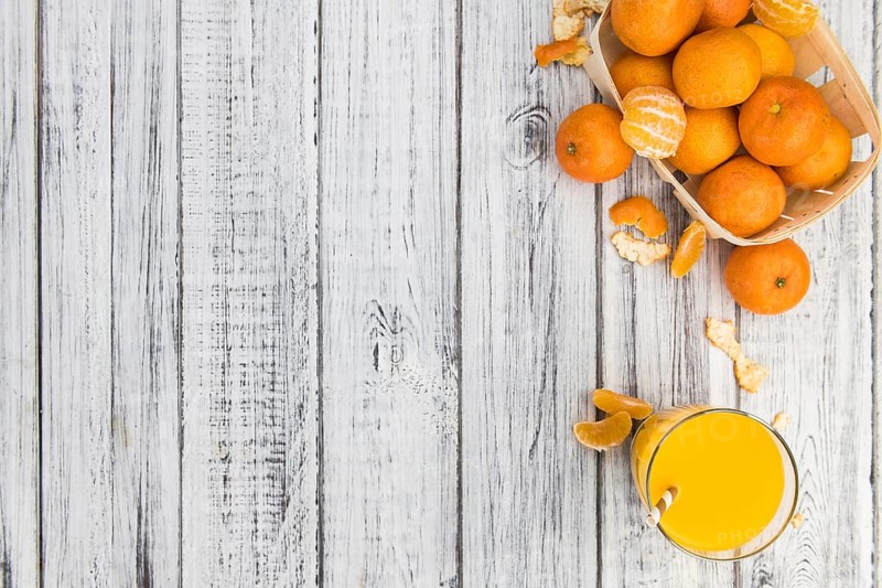 Wooden table with fresh homemade Tangerine Juice (close-up shot, selective focus)
