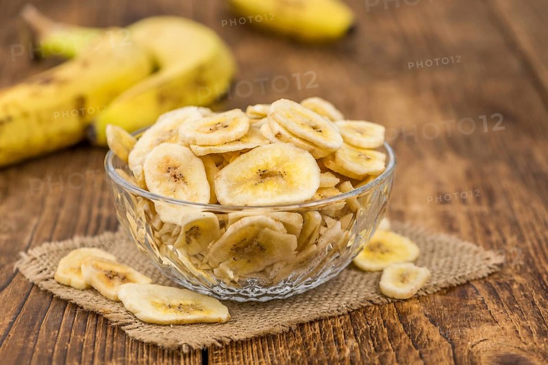 Homemade Dried Banana Chips on an wooden table as detailed close-up shot, selective focus