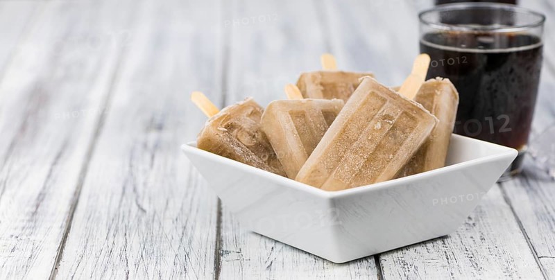 Fresh made Cola Popsicles on wooden background (selective focus, close-up shot)