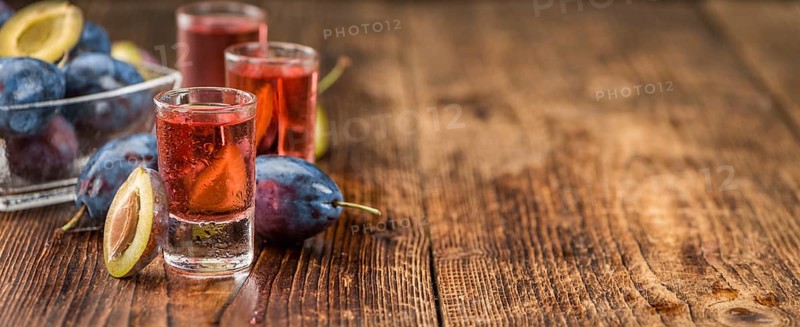 Homemade Plum Liqueur on an wooden table as detailed close-up shot, selective focus