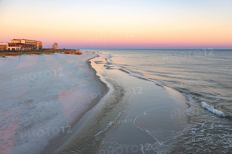 Tow women walking along the Gulf of Mexico beach as the sun rises over the Gulf of Mexico at Gulf Shores, Alabama