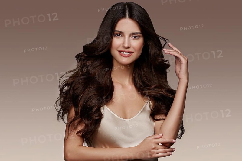 Beautiful brown-haired girl with a perfectly curls hair, and classic make-up. Beauty face and hair. Picture taken in the studio