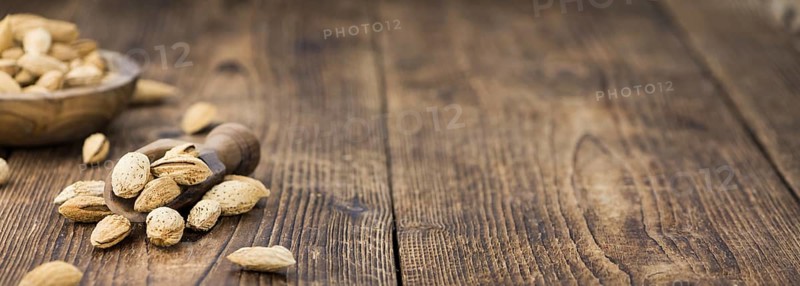 Roasted Almonds (in shell) on an old wooden table (close-up shot, selective focus)