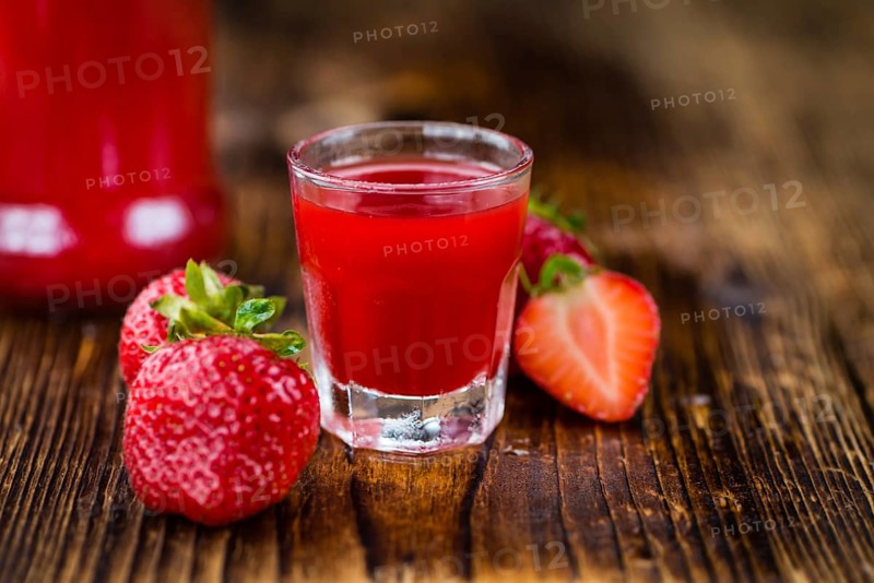 Homemade Strawberry liqueur on an wooden table as detailed close-up shot, selective focus