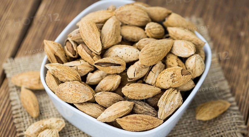 Roasted and salted Almonds (with shell) on a vintage background (close-up shot)