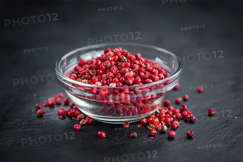 Portion of Pink Peppercorns on a rustic slate slab, selective focus, close-up shot