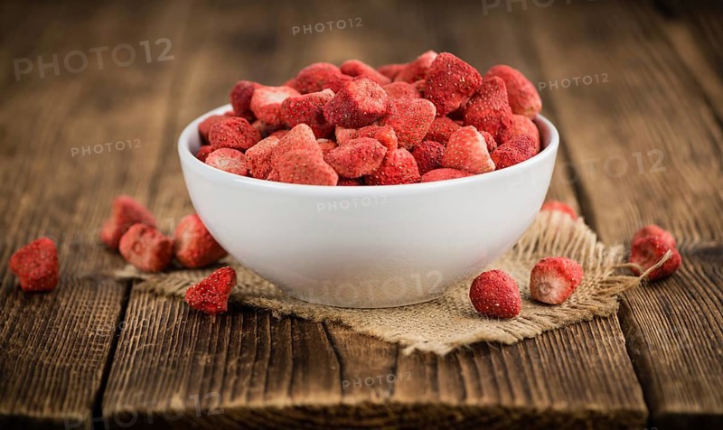 Strawberries (dried) as high detailed close-up shot on a vintage wooden table, selective focus