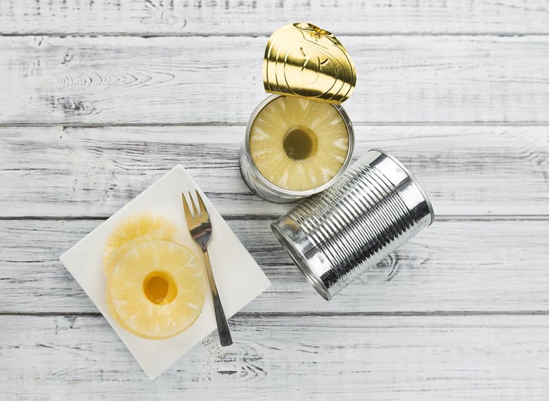 Preserved Pineapple Rings as high detailed close-up shot on a vintage wooden table, selective focus