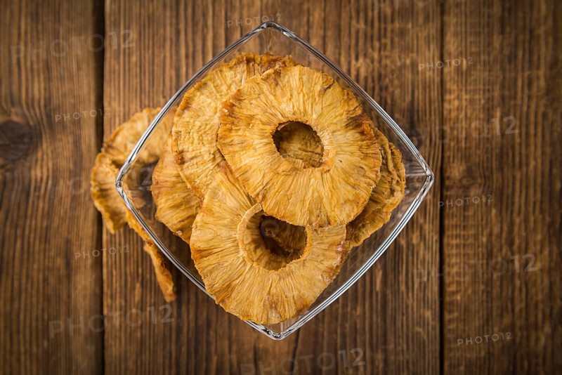 Pineapple rings (dried) on rustic wooden background as close-up shot