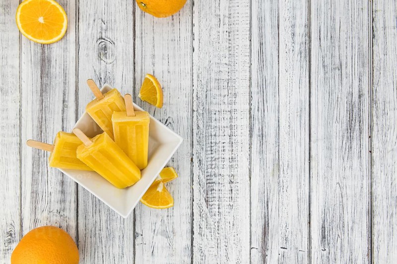 Some fresh made Popsicles (close-up shot, selective focus) on a wooden background