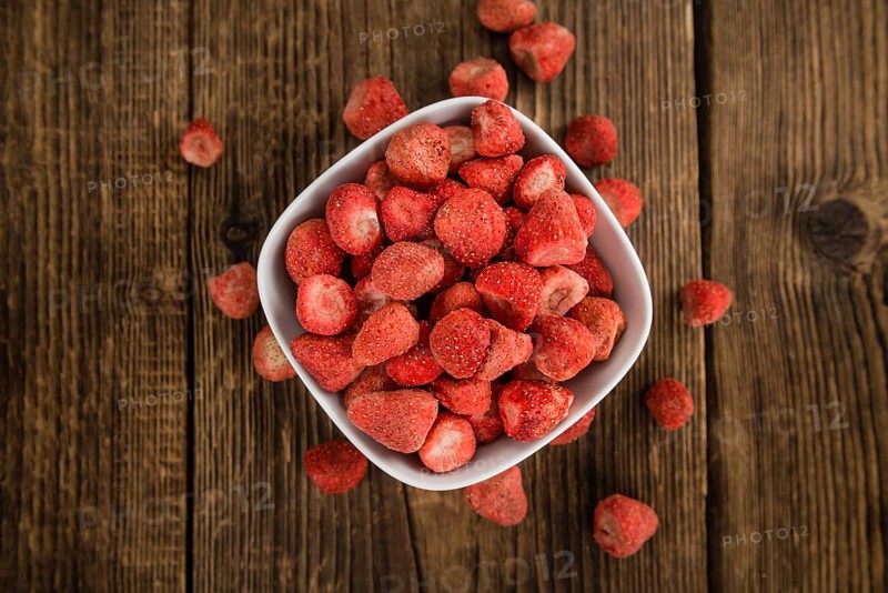 Strawberries (dried) as high detailed close-up shot on a vintage wooden table, selective focus
