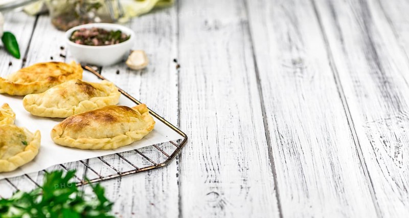 Portion of healthy Empanadas on an old wooden table (selective focus, close-up shot)