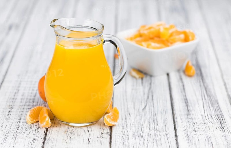 Wooden table with fresh homemade Tangerine Juice (close-up shot, selective focus)