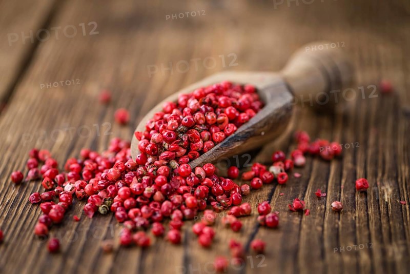 Pink Peppercorns on an old wooden table as detailed close-up shot, selective focus