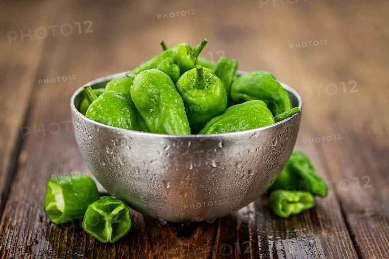 Raw Pimientos on an old wooden table as detailed close-up shot, selective focus