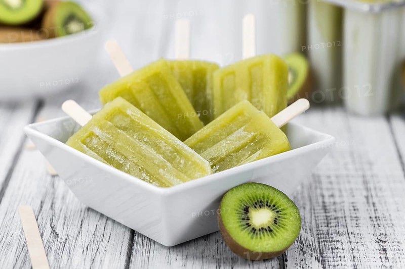 Some fresh Kiwi Popsicles on wooden background (selective focus, close-up shot)