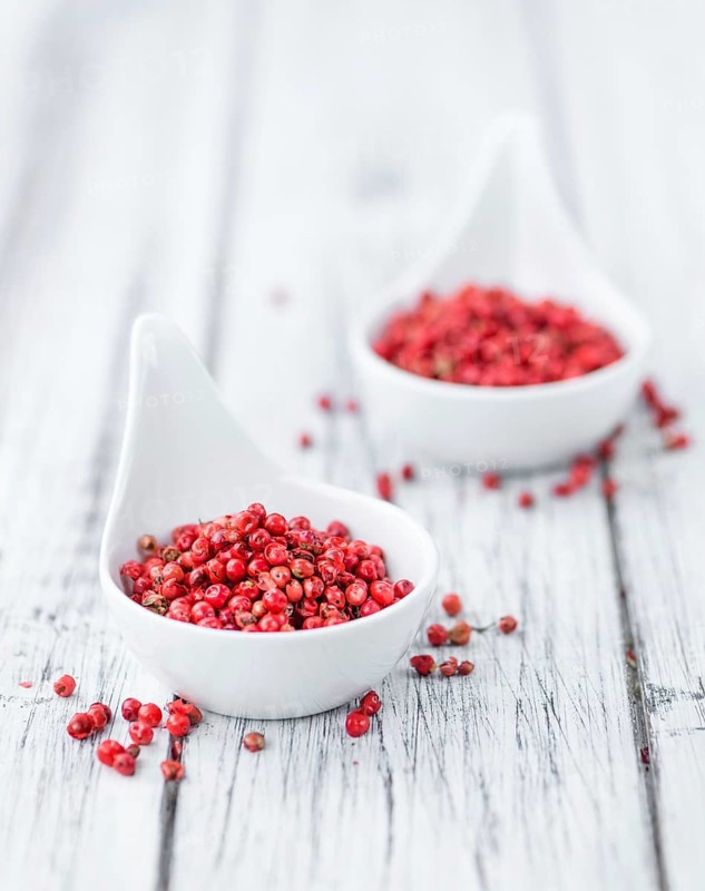 Pink Peppercorns on an old wooden table as detailed close-up shot, selective focus