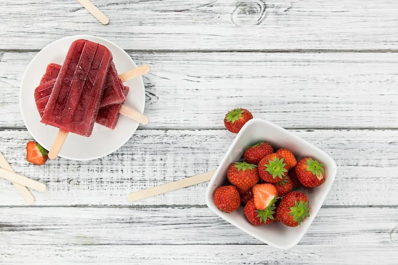 Homemade Strawberry Popsicles (close-up shot, selective focus) on vintage background