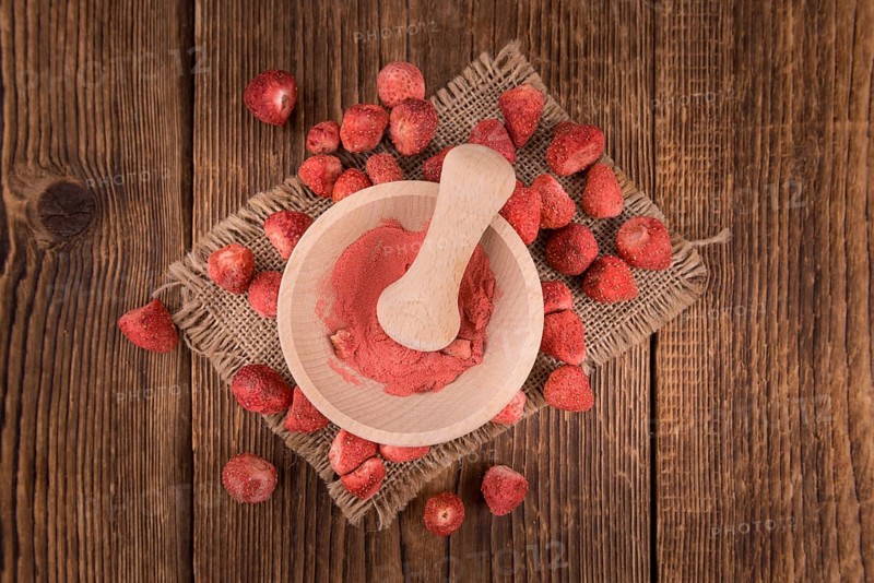 Strawberry powder as high detailed close-up shot on a vintage wooden table, selective focus