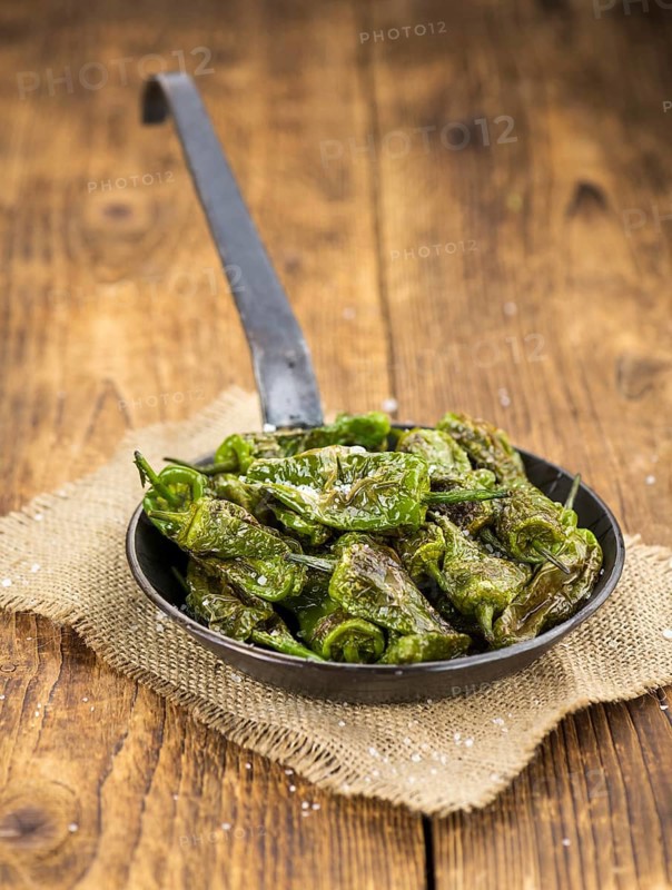 Pimientos de Padron on an old wooden table as detailed close-up shot, selective focus