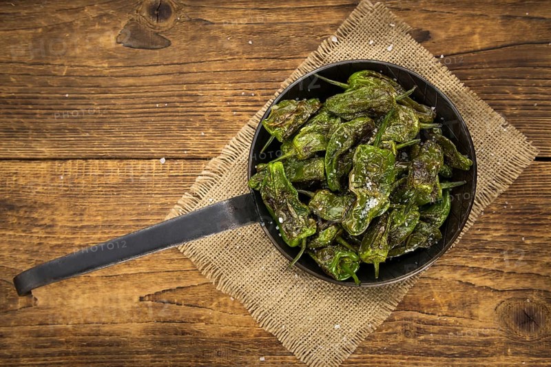 Pimientos de Padron on rustic wooden background as close-up shot