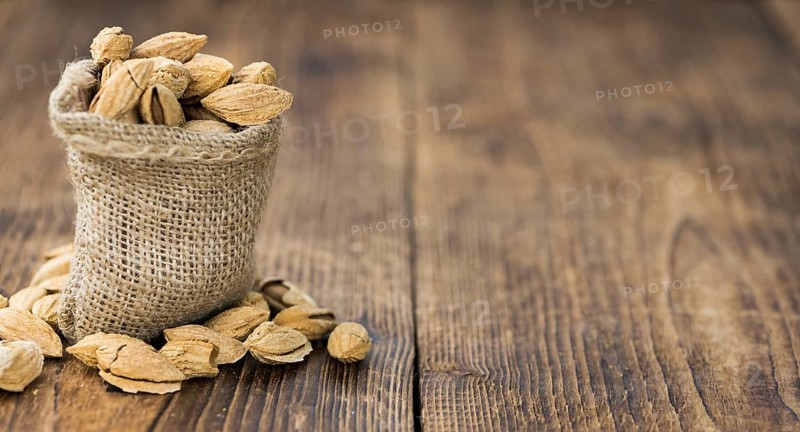 Roasted and salted Almonds (with shell) on a vintage background (close-up shot)