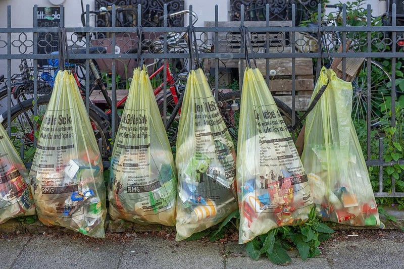 Yellow bags for plastic waste, hanging on a garden fence in front of a house entrance, waste separation, Bremen, Germany, Europe