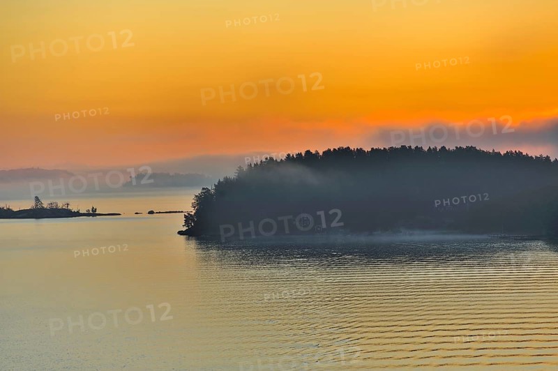 The Stockholm Archipelago along the Swedish coastline seen from the Baltic Sea with dramatic orange sunrise, Sweden, Europe