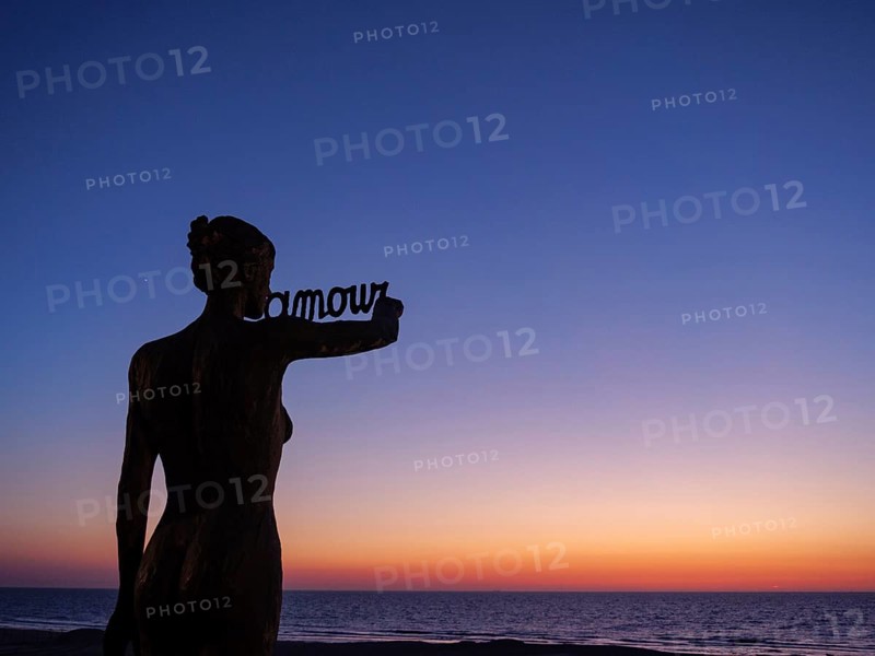 Beautiful dusk on the beach, silhouette of a statue against the dark blue sky, de haan, Belgium, Europe
