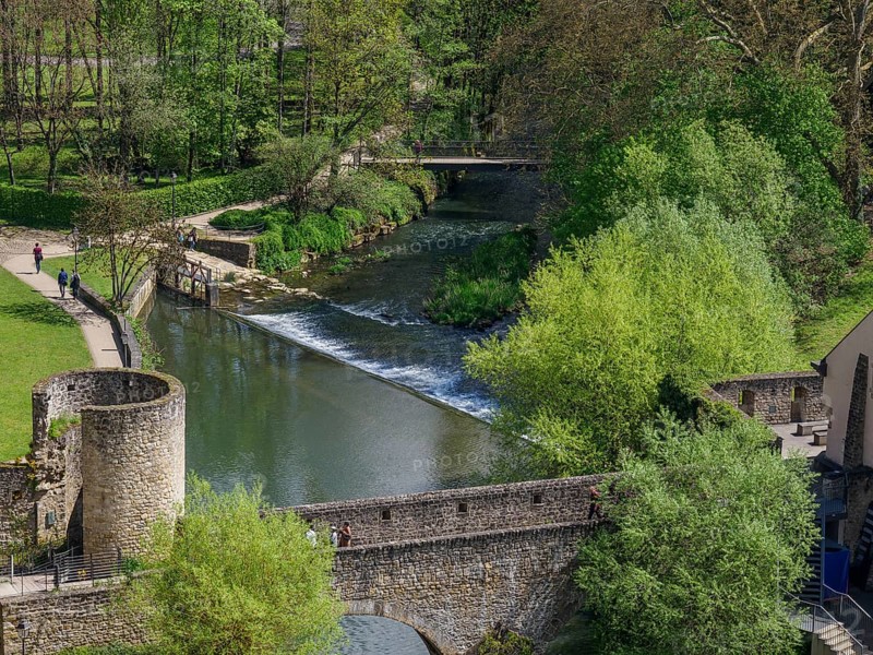 A river with a bridge and ruins in the middle of a green park landscape, walkers enjoying nature, Luxembourg City, Luxembourg, Europe
