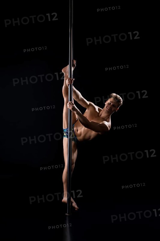 Young fair athletic man exercising on pylon studio shot