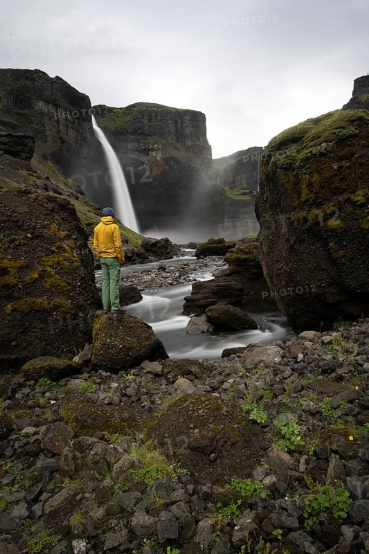 Young man with yellow jacket standing in front of waterfall, Haifoss and Granni waterfall at a canyon, Fossá í Thjórsárdal, with river í Thjórsárdal, long exposure, dramatic landscape, Hekla, Iceland, Europe