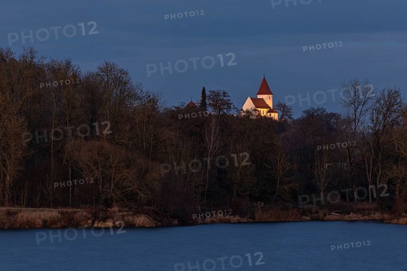 Illuminated church of Schaefstall near Donauworth above a lake in Bavaria