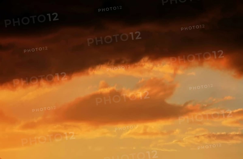 Cloudy sky at sunset. The sky is visible through a gap in the clouds. The image conveys a mood of an impending storm or bad weather