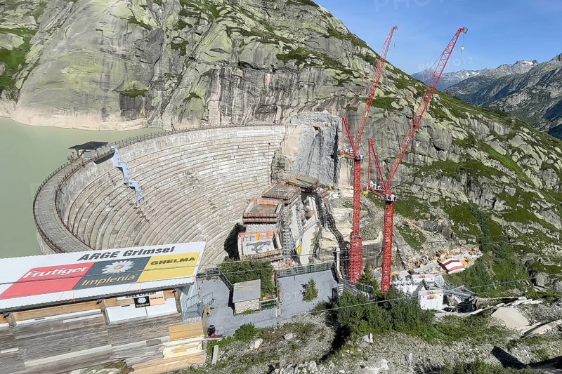 View from Grimsel Hospice Grimselhospiz to construction site of new dam for enlargement of reservoir Grimselsee replacement dam Spitallamm on the Grimsel in the Bernese Oberland, left old dam next to Grimsel Hospice Grimselhospiz, right two big red cranes, Guttanen, Canton Bern, Switzerland, Europe