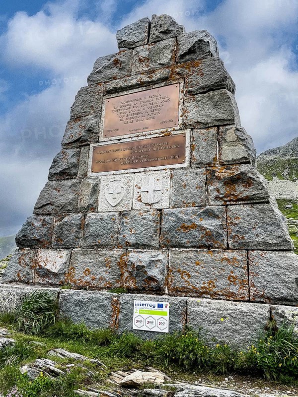 Memorial stone Monument on border between Switzerland and Italy with inscriptions two commemorative plaques in memory of renovation in 2022 and centenary 1821 1822 1921 1922 of pass road road Alpine pass Mountain pass over Splügenpass Passo dello Spluga, Canton Graubünden, Switzerland, Lombardy, Italy, Europe