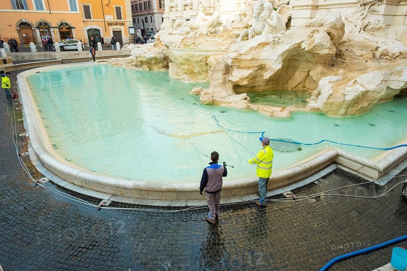 Rome, Italy, January 5, 2018: City workers cleaning coins from Trevi Fountain with water vacuum, Europe