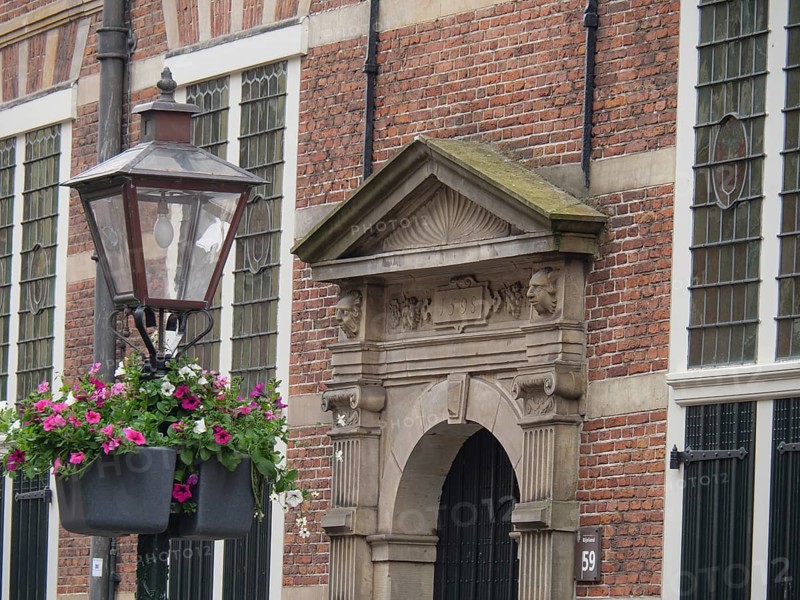 Historic façade with hanging flower baskets and an ornate lantern in the foreground, Leiden, Netherlands