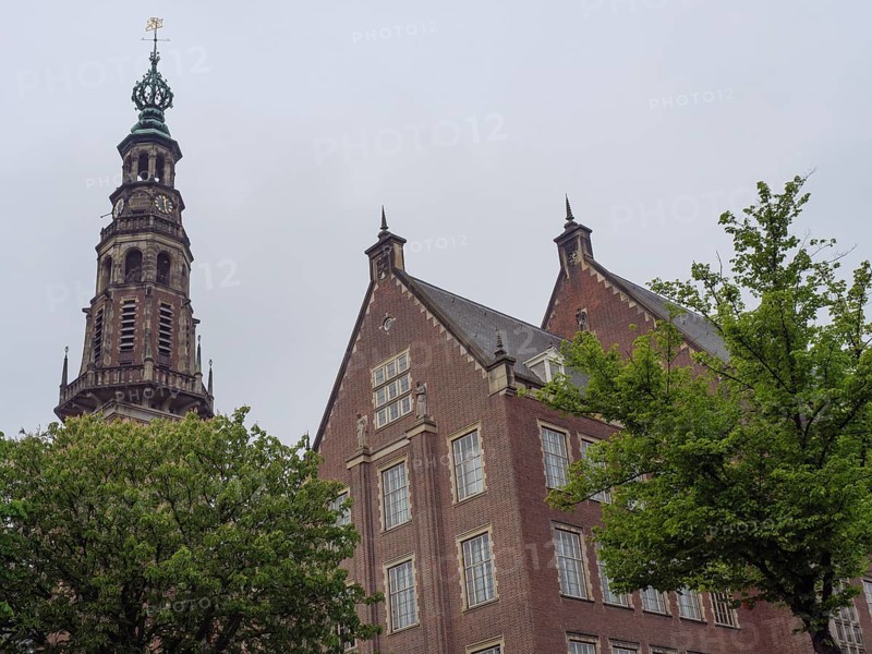 Historic building with imposing church tower and trees in the foreground under a grey sky, Leiden, Netherlands