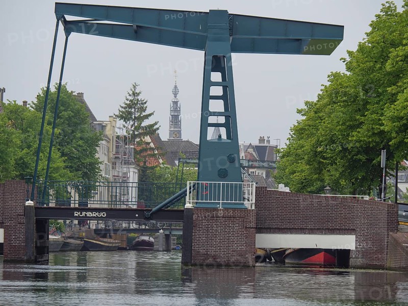 A bascule bridge over a canal with a church tower in the background and tree-lined streets, Leiden, Netherlands