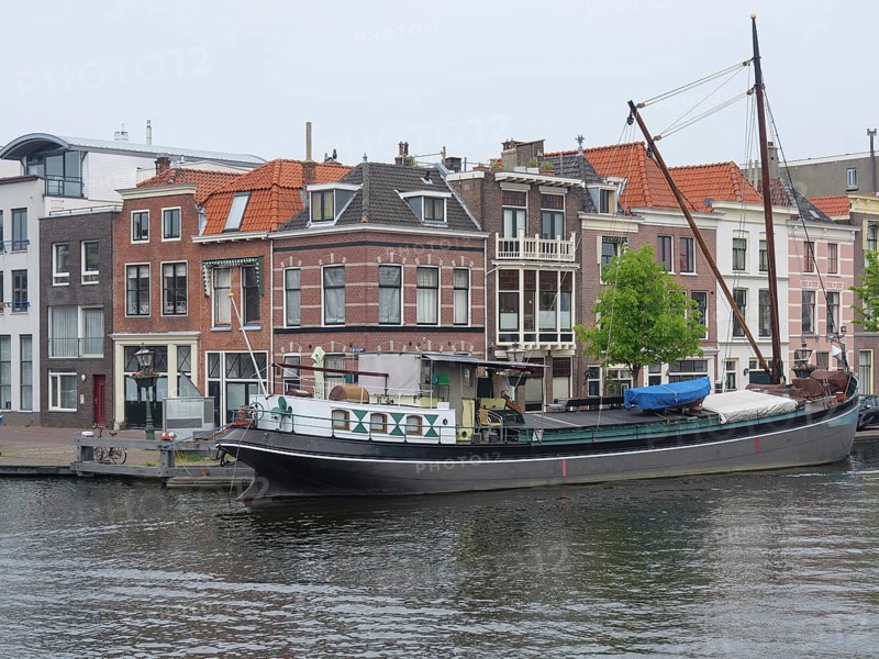 Boat on a canal next to gabled houses in a Dutch town, Leiden, Netherlands