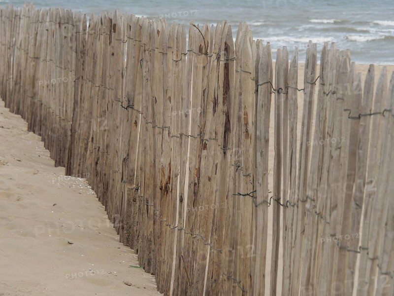 A wooden fence along a beach with a view of the sea, Leiden, Netherlands