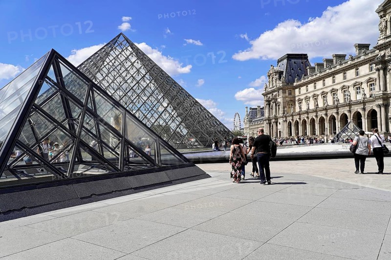 Glass pyramid in the courtyard of the Palais du Louvre, Paris, France, Europe, People walking between the buildings and the glass pyramid of the Louvre in Paris in sunny weather, Europe