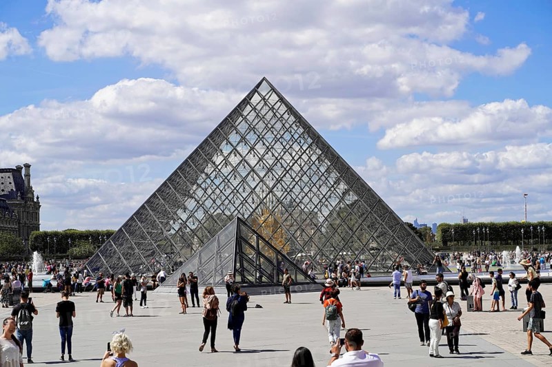 Glass pyramid in the courtyard of the Palais du Louvre, Paris, France, Europe, Glass pyramid of the Louvre in Paris with many tourists in front of it under a cloudy sky, Europe