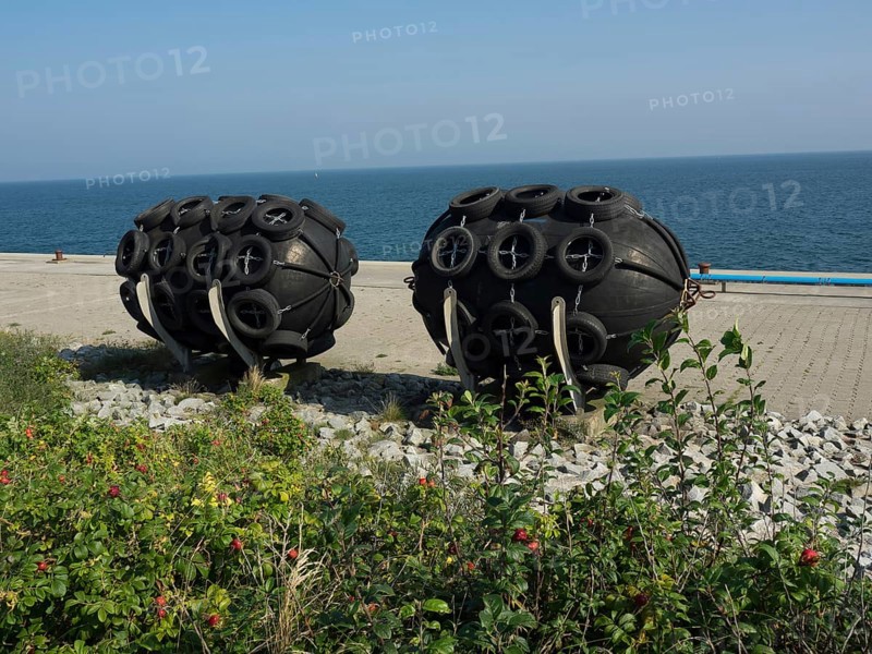Black round fenders on the shore next to the blue sea under the clear sky, helgoland, germany