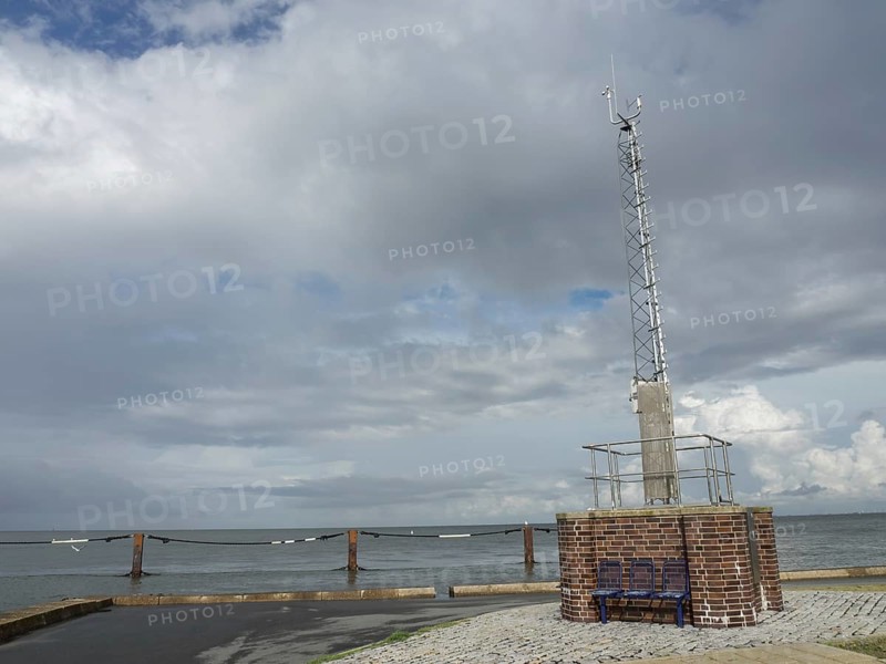 A radio mast on a brick base by the sea under a cloudy sky, cuxhaven, germany