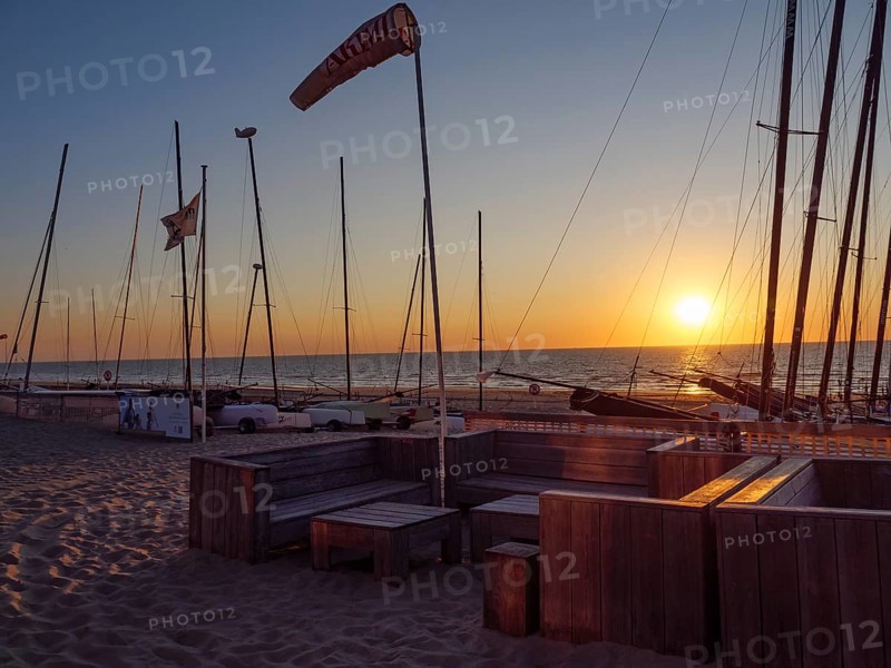 Sailboats and empty seats on the beach at sunset with calm sea and sandy bottom, De Haan, Flanders, Belgium, Europe
