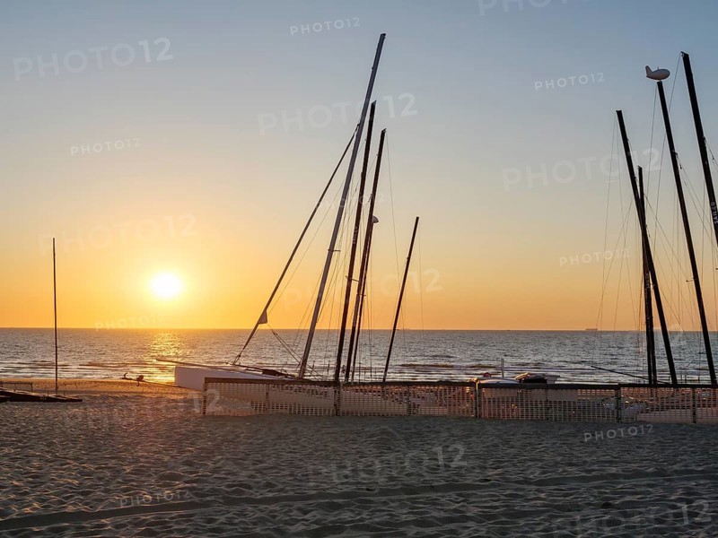 Beach with boat masts at sunset, calm and peaceful atmosphere, sand and sea, warm colours, De Haan, Flanders, Belgium, Europe