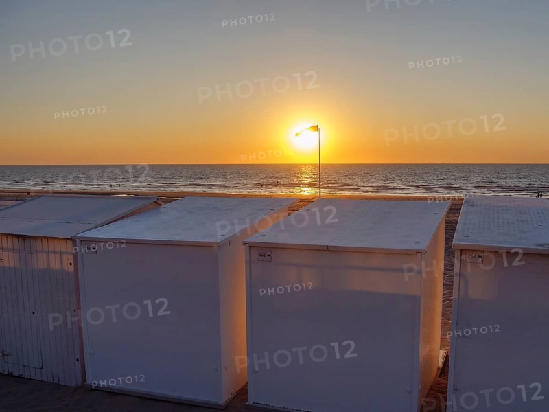 Sunset over the sea, beach with white huts, quiet and peaceful atmosphere with a warm light, De Haan, Flanders, Belgium, Europe